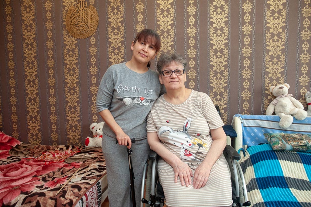 Пожилая женщина в инвалидной коляске и молодая женщина с тростью