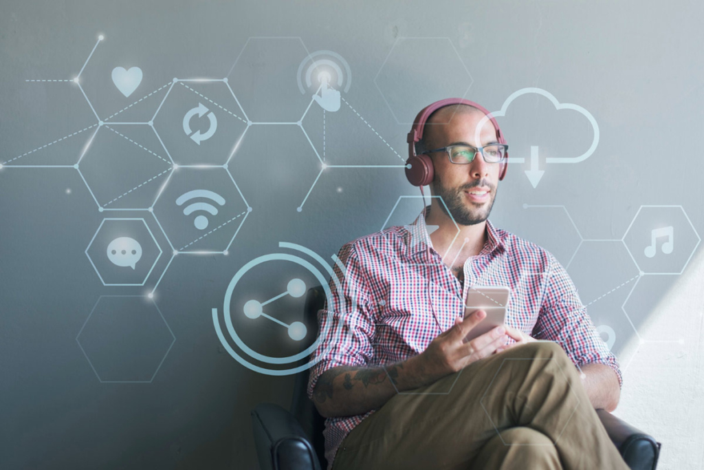 Мужчина сидит в кресле с телефоном и в наушниках