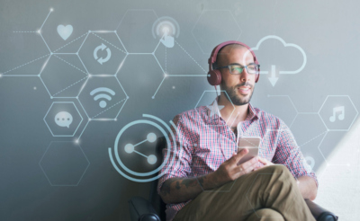 Мужчина сидит в кресле с телефоном и в наушниках