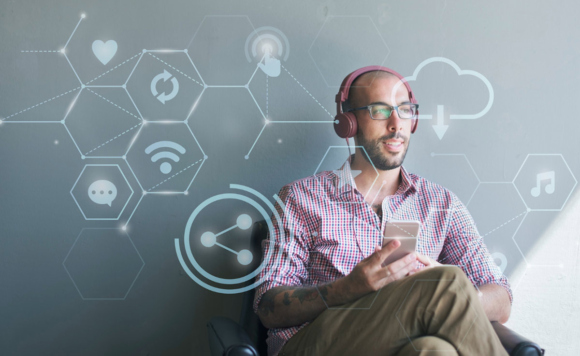 Мужчина сидит в кресле с телефоном и в наушниках