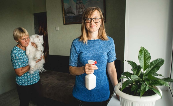 Девушка с пульверизатором опрыскивает растения