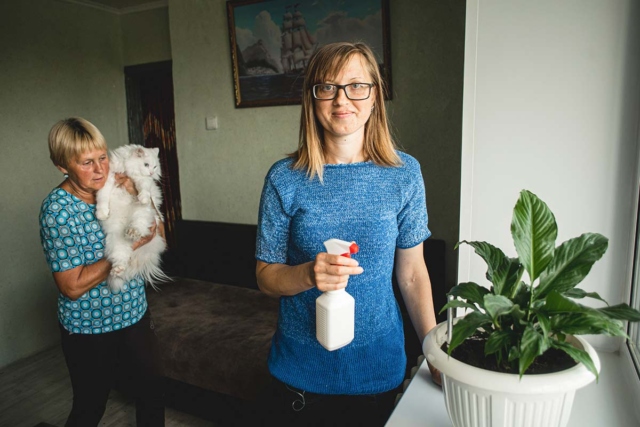 Девушка с пульверизатором опрыскивает растения