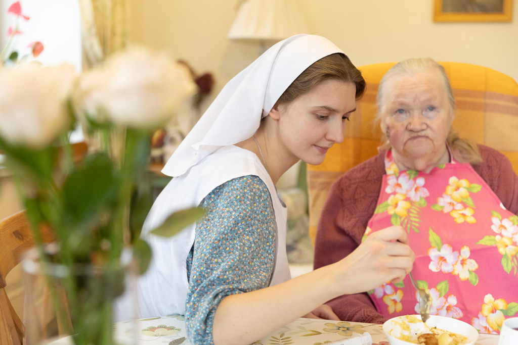 Сестра милосердия кормит немощную бабушку