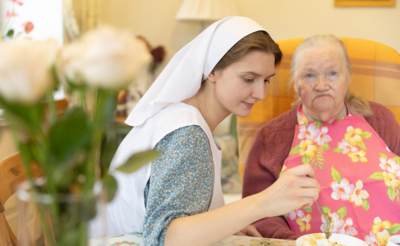 Сестра милосердия кормит немощную бабушку