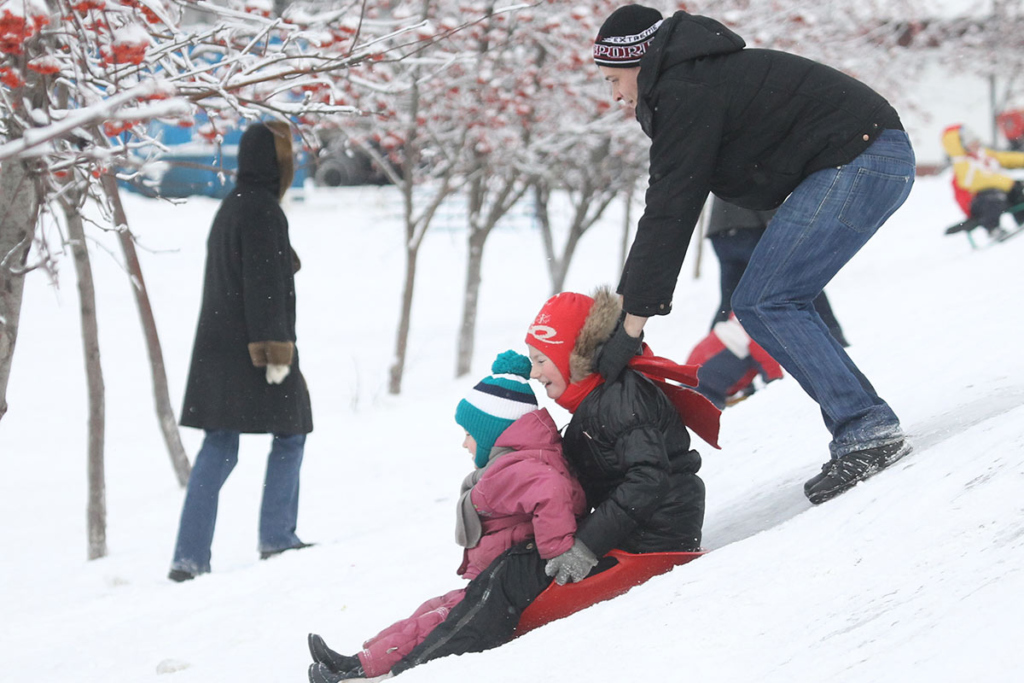 Папа с детьми катается с ледяной горки