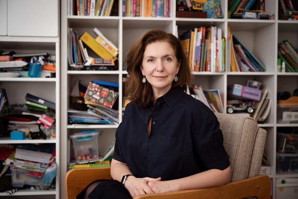 Портрет молодой женщины на фоне полок с игрушками и книгами 