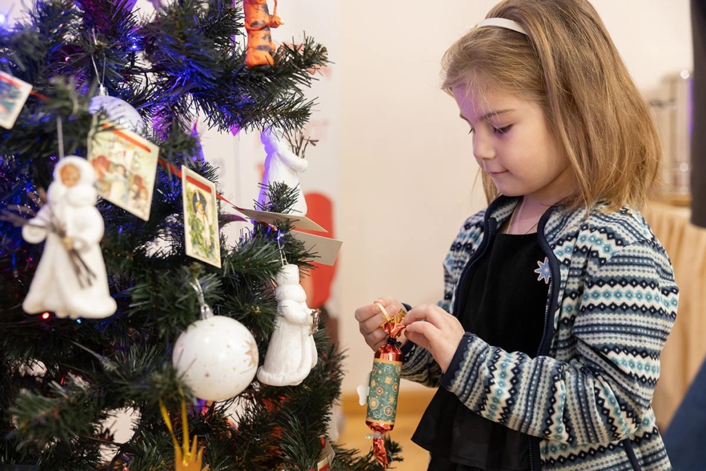 Девочка вешает игрушки на елку