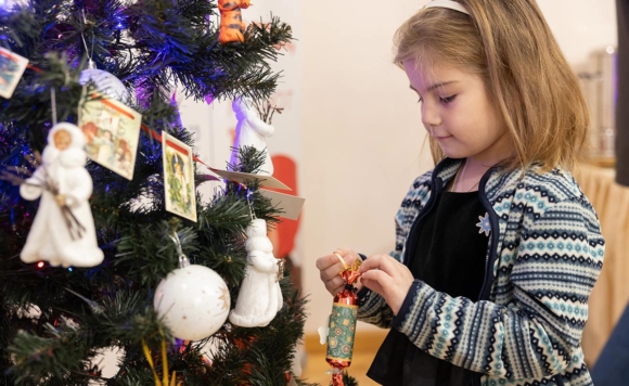 Девочка вешает игрушки на елку