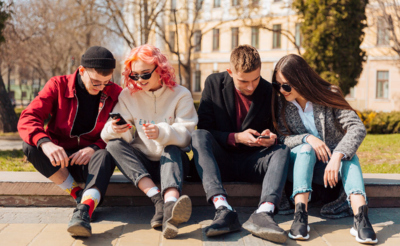 молодые люди сидят в телефонах на улицу