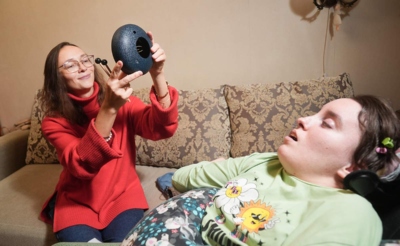 Молодая женщина с музыкальным инструментом и больная девушка в инвалидной коляске