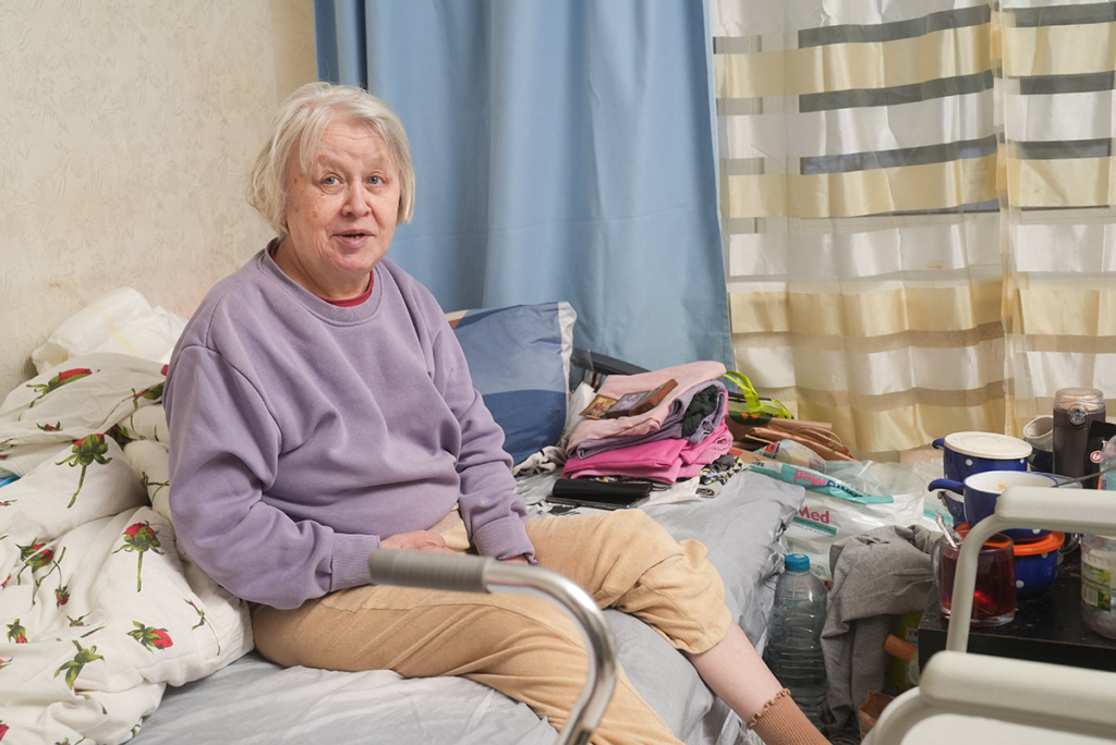 Пожилая женщина сидит на кровати