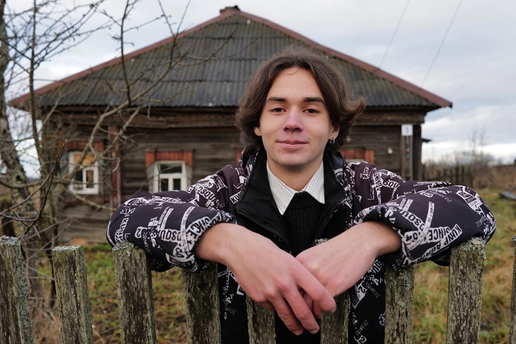 Портрет юноши на фоне старого деревенского дома