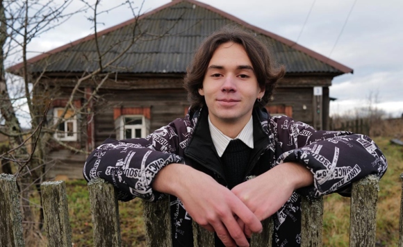 Портрет юноши на фоне старого деревенского дома