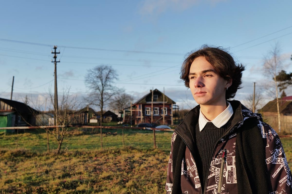 Юноша на фоне деревенской улицы 