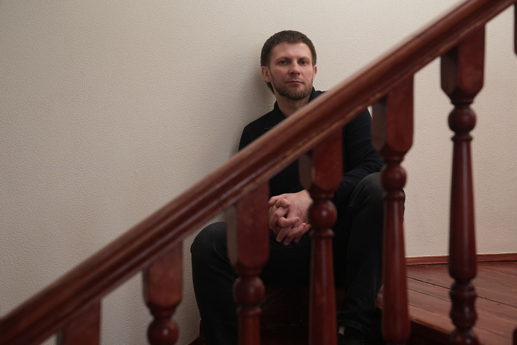 Молодой мужчина сидит на лестнице