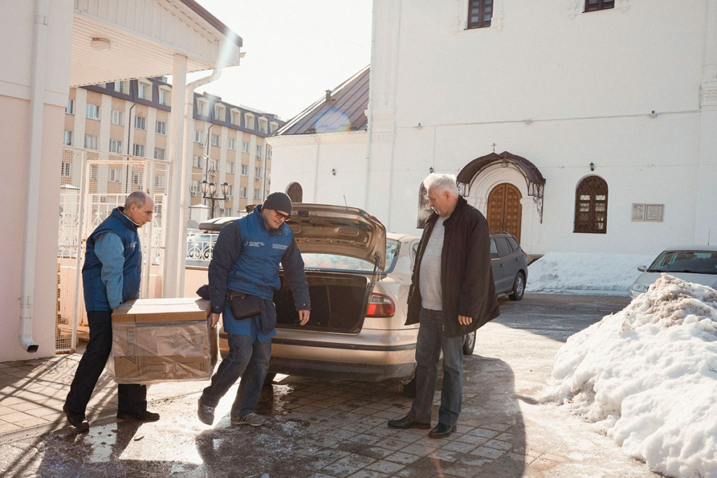Мужчины грузят генератор в багажник машины 