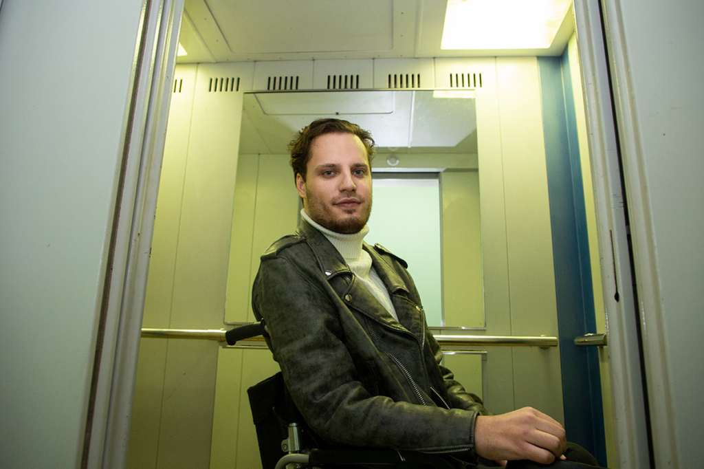 Молодой мужчина в куртке-косухе в дверях лифта