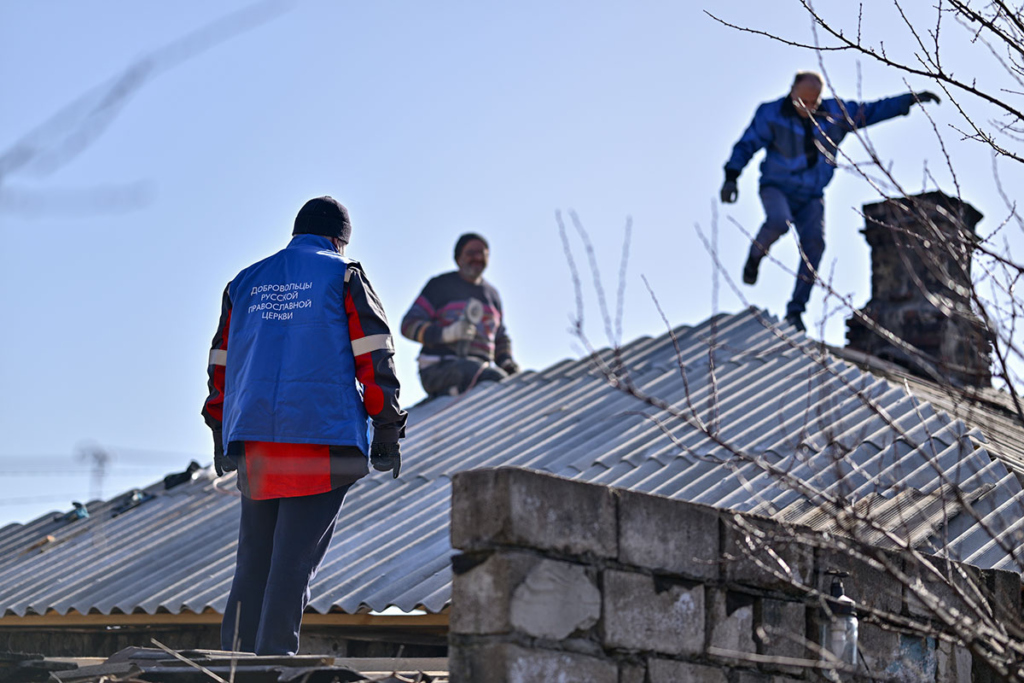 добровольцы-ремонтники на крыше частного дома делают ремонт