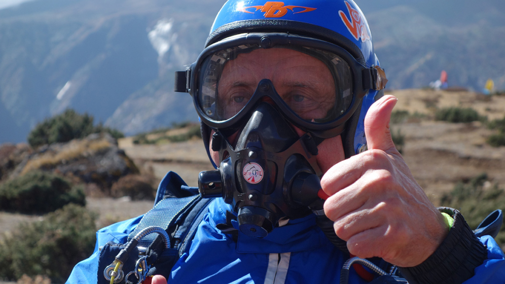 Мужчина в парашютном снаряжении и кислородной маске 