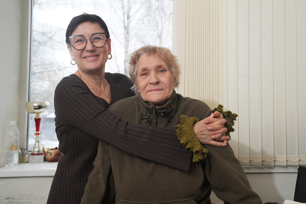 Женщина средних лет обнимает пожилую женщину