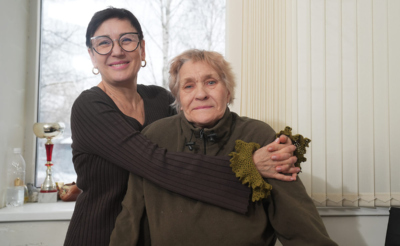 Женщина средних лет обнимает пожилую женщину