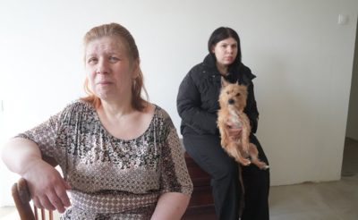 Женщина среднего возраста и ее дочь с собачкой на фоне стены в квартире