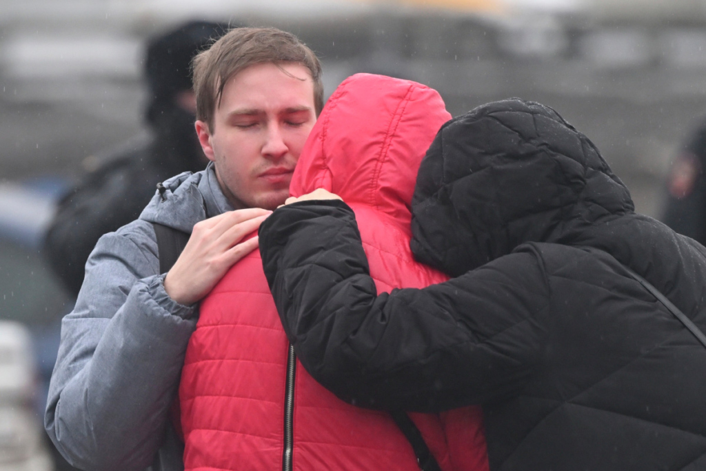 Люди у здания концертного зала "Крокус Сити Холл", где произошла стрельба, и начался пожар. Как минимум три человека в камуфляже открыли огонь в фойе здания, есть погибшие и раненые