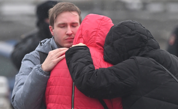 Люди у здания концертного зала "Крокус Сити Холл", где произошла стрельба, и начался пожар. Как минимум три человека в камуфляже открыли огонь в фойе здания, есть погибшие и раненые