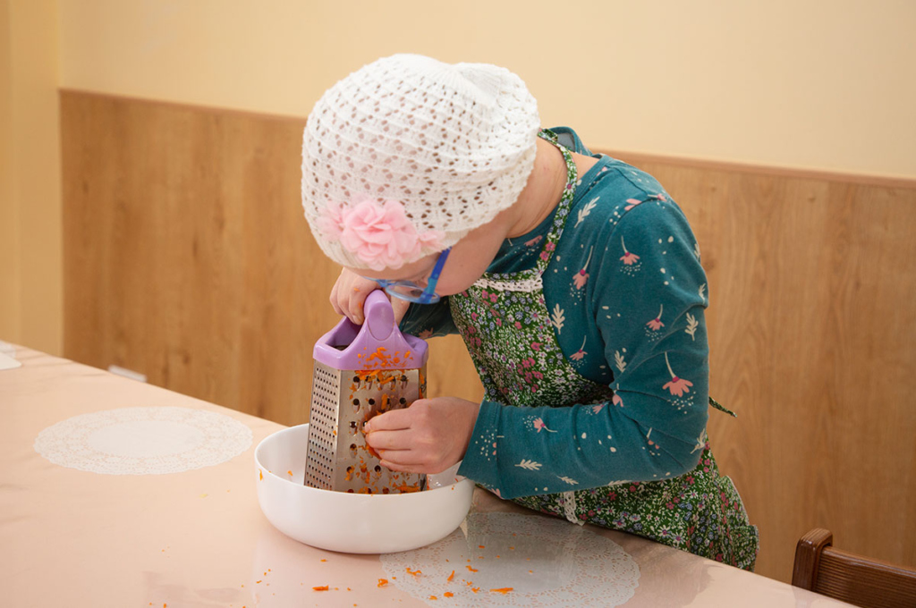 Девочка трет овощи на тёрке 