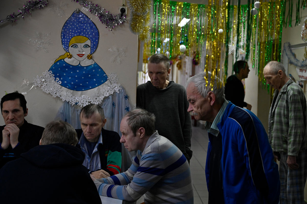 Мужчины - пациенты ПНИ, на стене новогодняя Снегурочка из бумаги