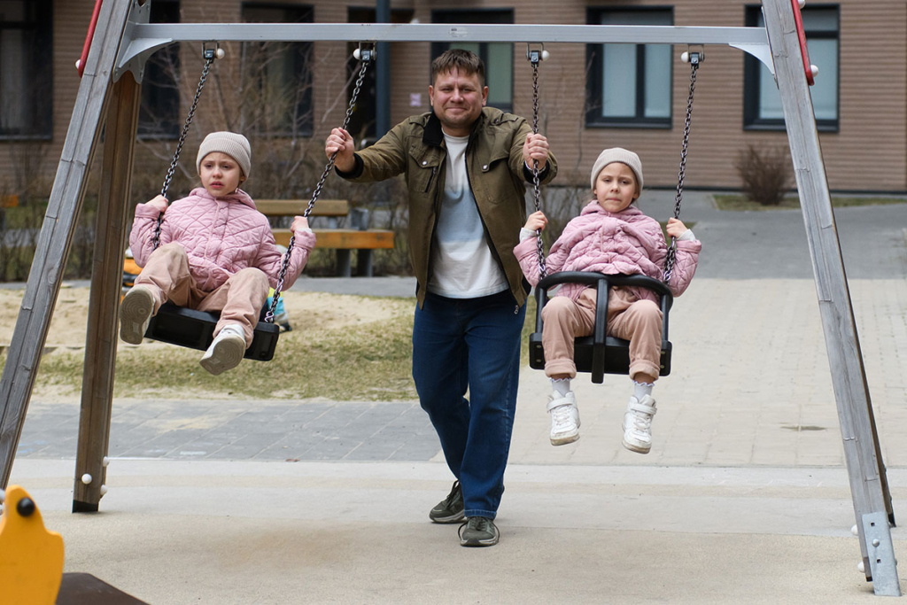 Папа качает дочек на качелях