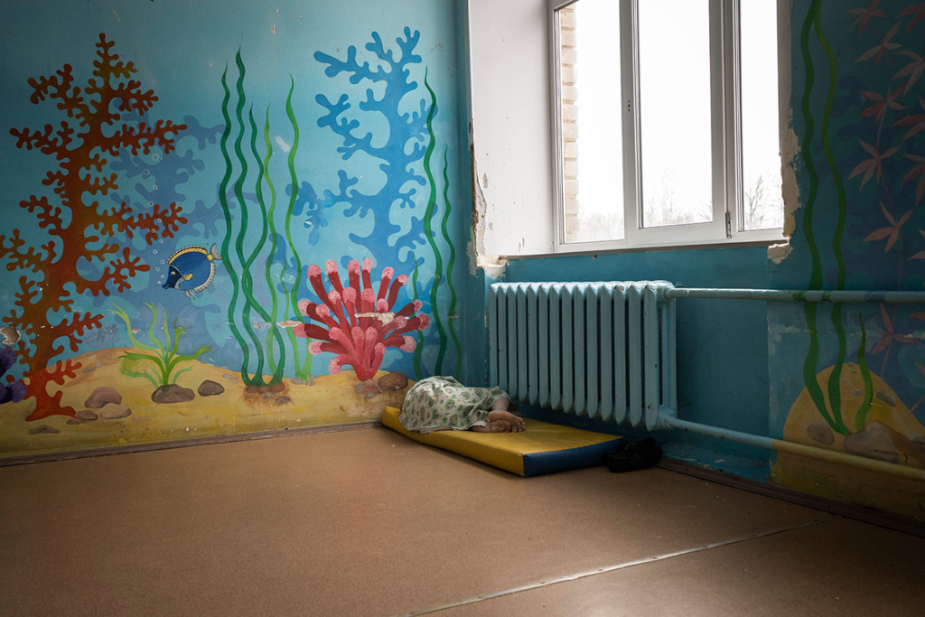 Человек лежит в углу комнаты на матрасе-мате