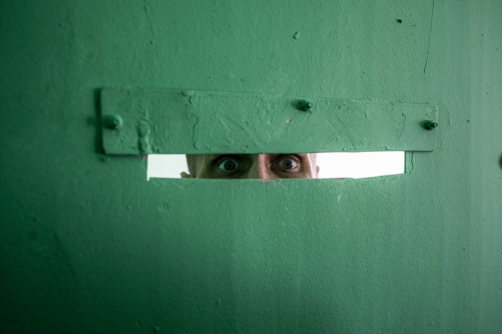 Мужчина смотрит в дверную щель
