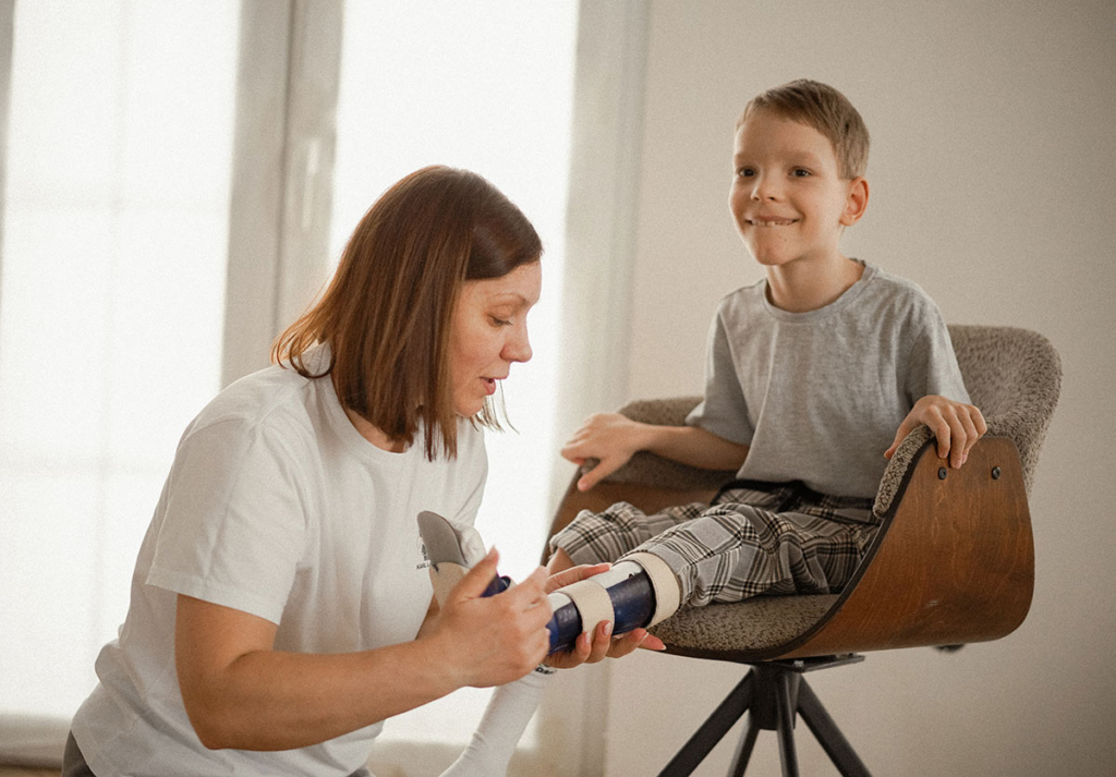 Мама одевает сыну ортезы 