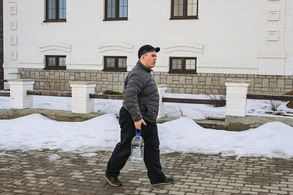 Юноша несет воду в 5-литровой бутылке 