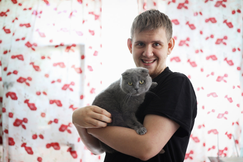 Молодой парень с кошкой на руках 