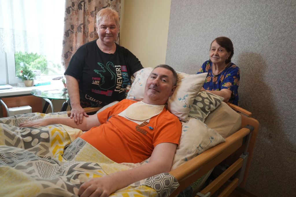Больной дежачий мужчина с сиделкой и мамой