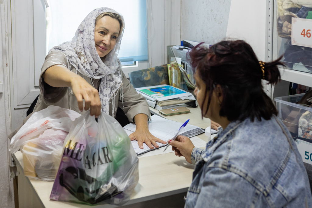 Женщина дает пакет с продуктами другой женщине