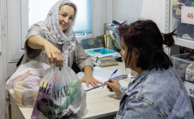 Женщина дает пакет с продуктами другой женщине